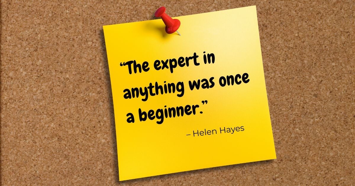 Cork bulletin board with a yellow pinned note that reads, “The expert in anything was once a beginner.” – Helen Hayes