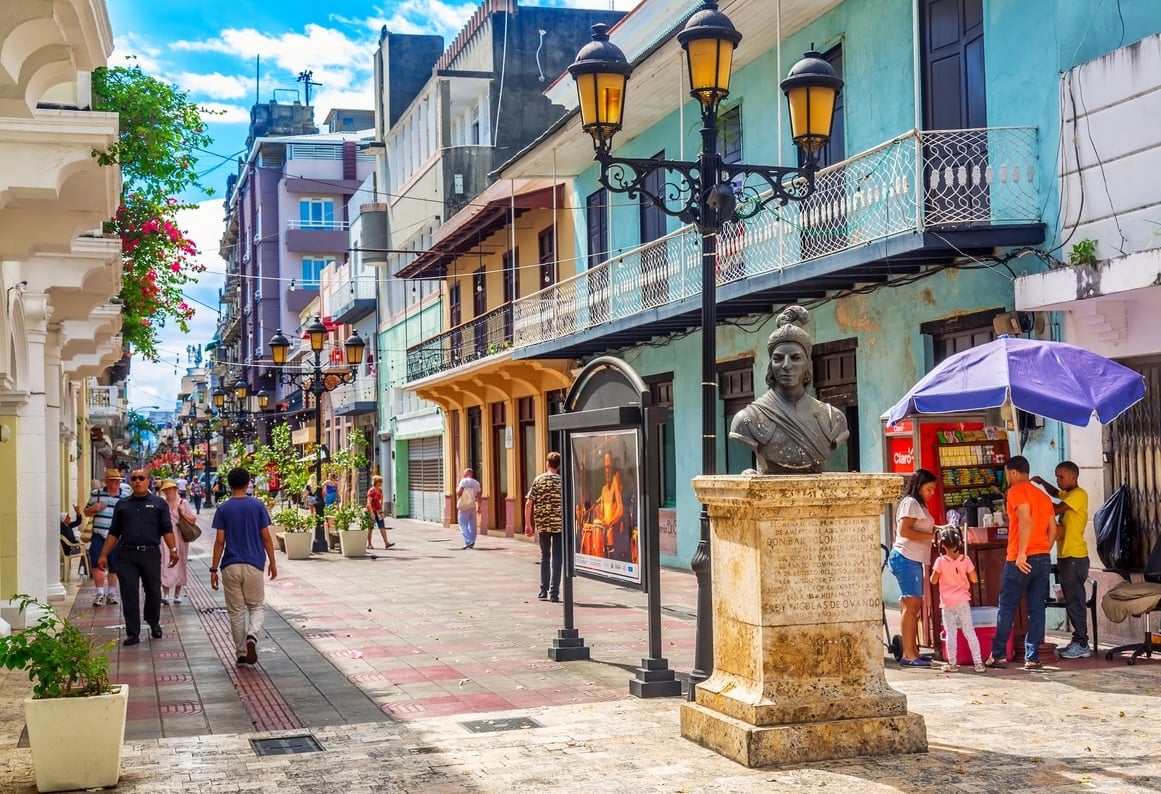 Colorful street scene in Santo Domingo with pedestrians, historic buildings, and local vendors in the Dominican Republic.