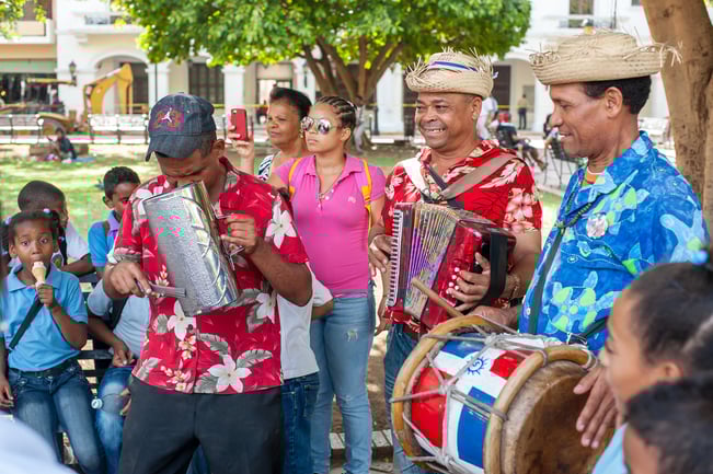 Street musicians in the Dominican Republic wearing colorful shirts and playing traditional Dominican instruments.