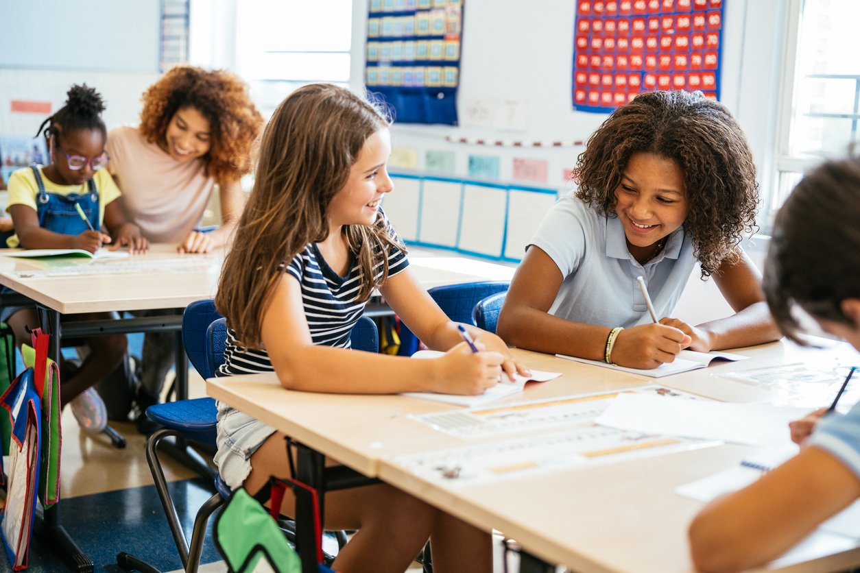Children sitting at desks in a classroom learning Spanish.