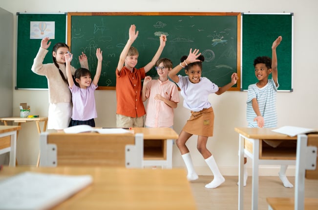 Children dancing in front of blackboard in a Spanish immersion class
