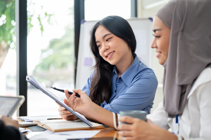 Two students in an English class reading from an ipad.