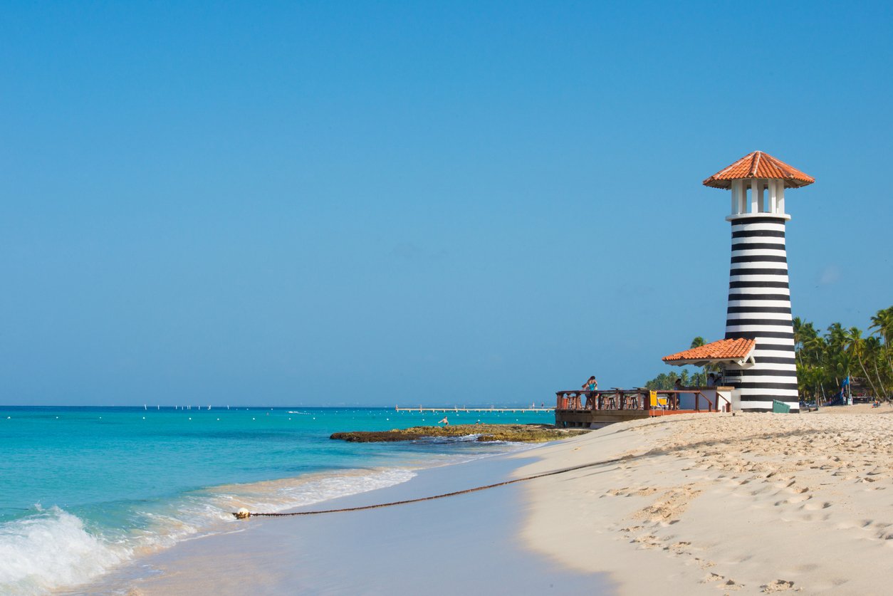 Striped blue and white lighthouse on beach in the Dominican Republic.
