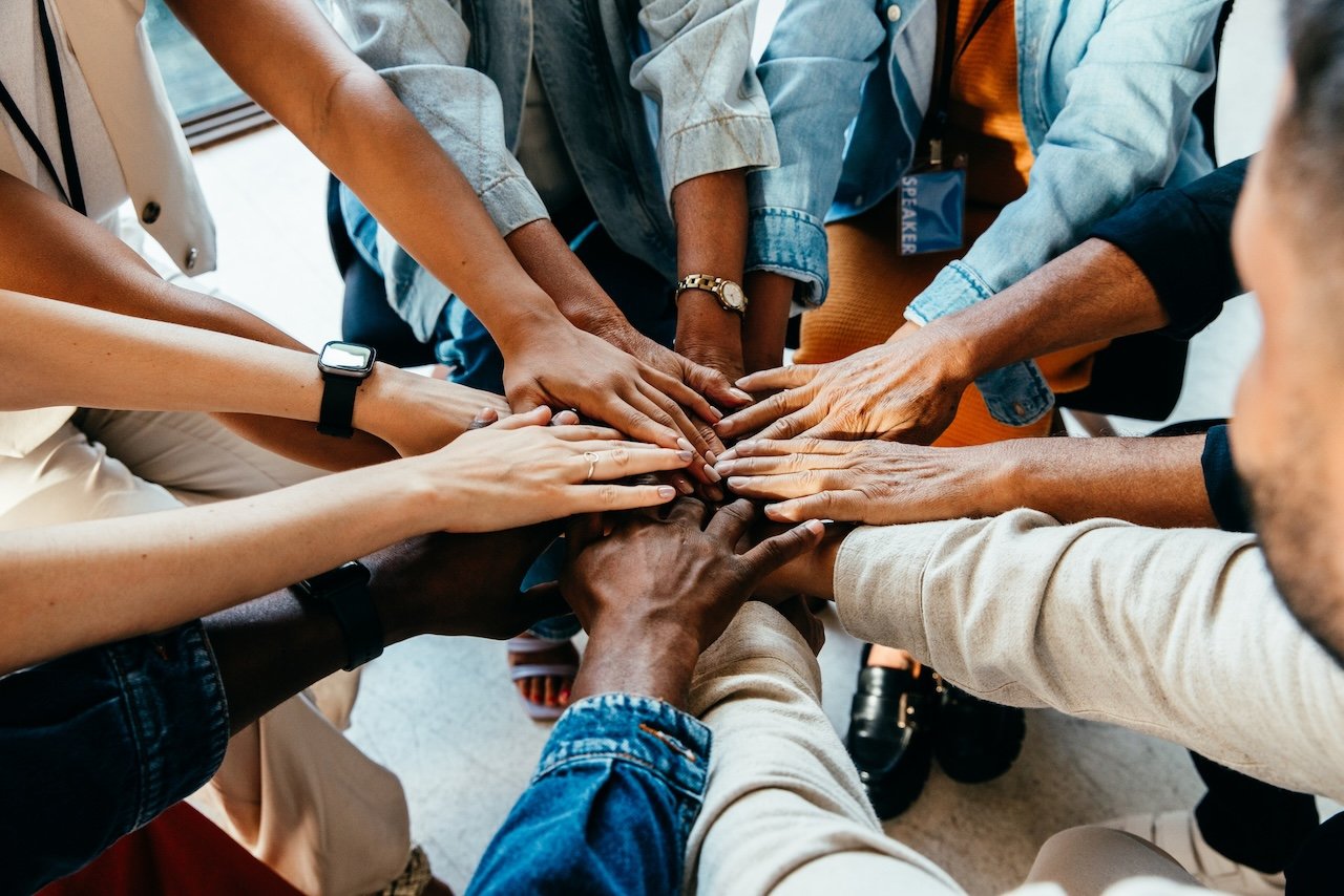 Coworkers standing in circle with hands overlapped.